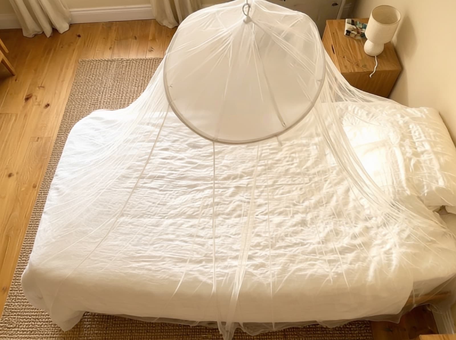 Overhead view of the Mosticare Rondo canopy's suspension ring and netting draped over a bed.