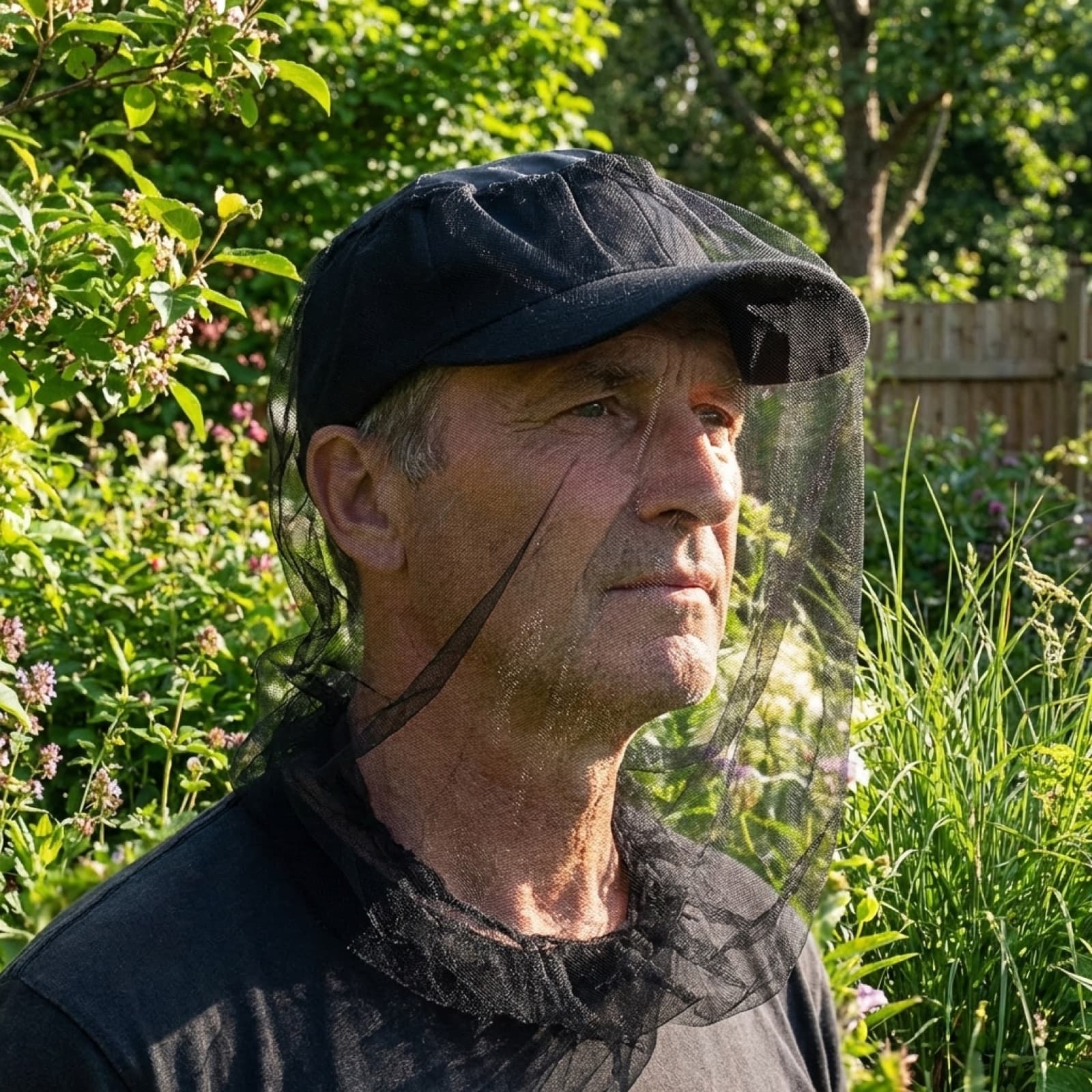 A man in a garden wearing the Mosticare Volto head net draped from a cap over his face.