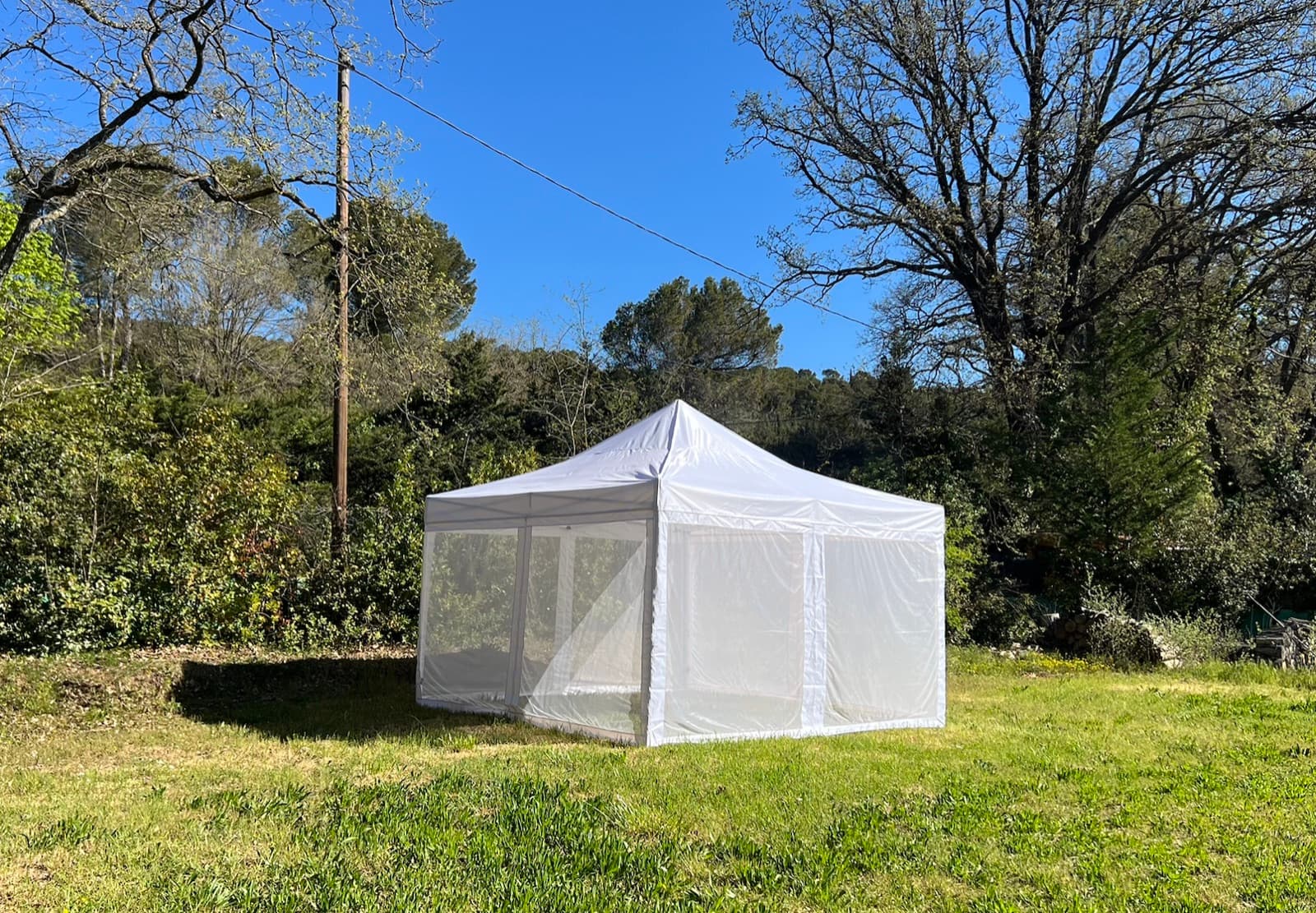 The Mosticare Terrazza gazebo with zip-up mesh walls standing in a Mediterranean garden.
