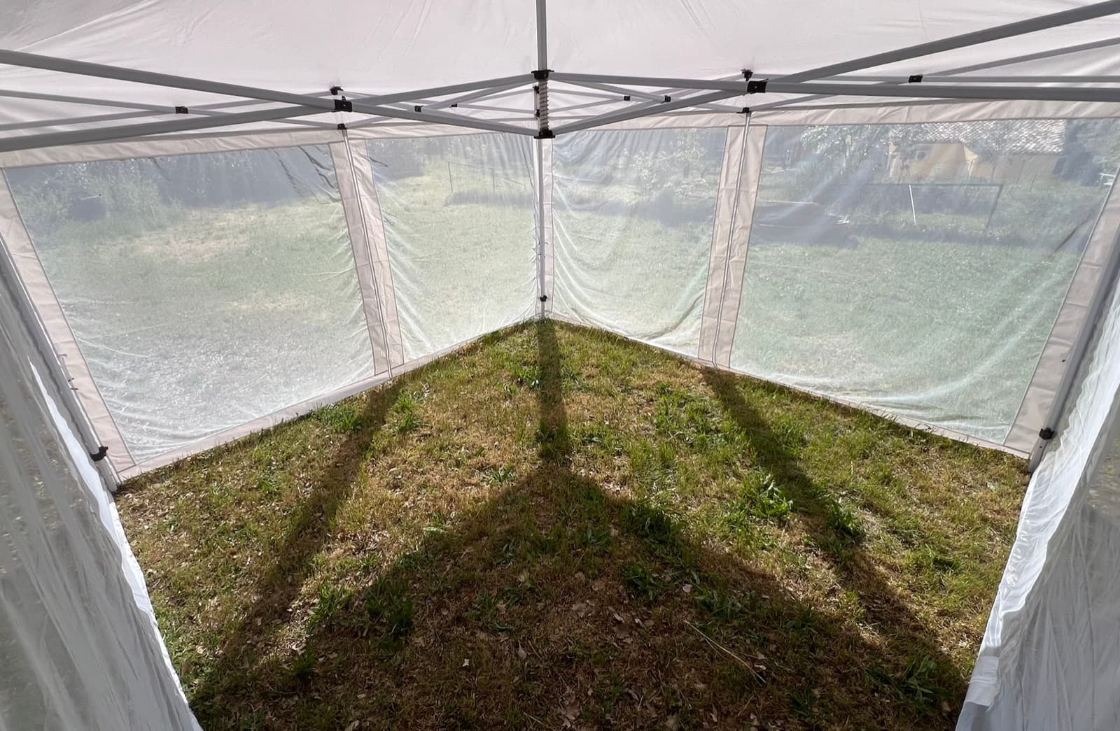 Interior of the Mosticare Terrazza gazebo, mesh walls enclosing a grassy floor.