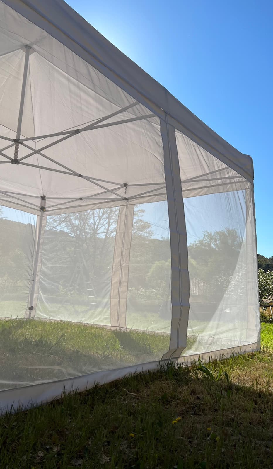 Detail of the Mosticare Terrazza gazebo's mesh wall and frame backlit by the sun.